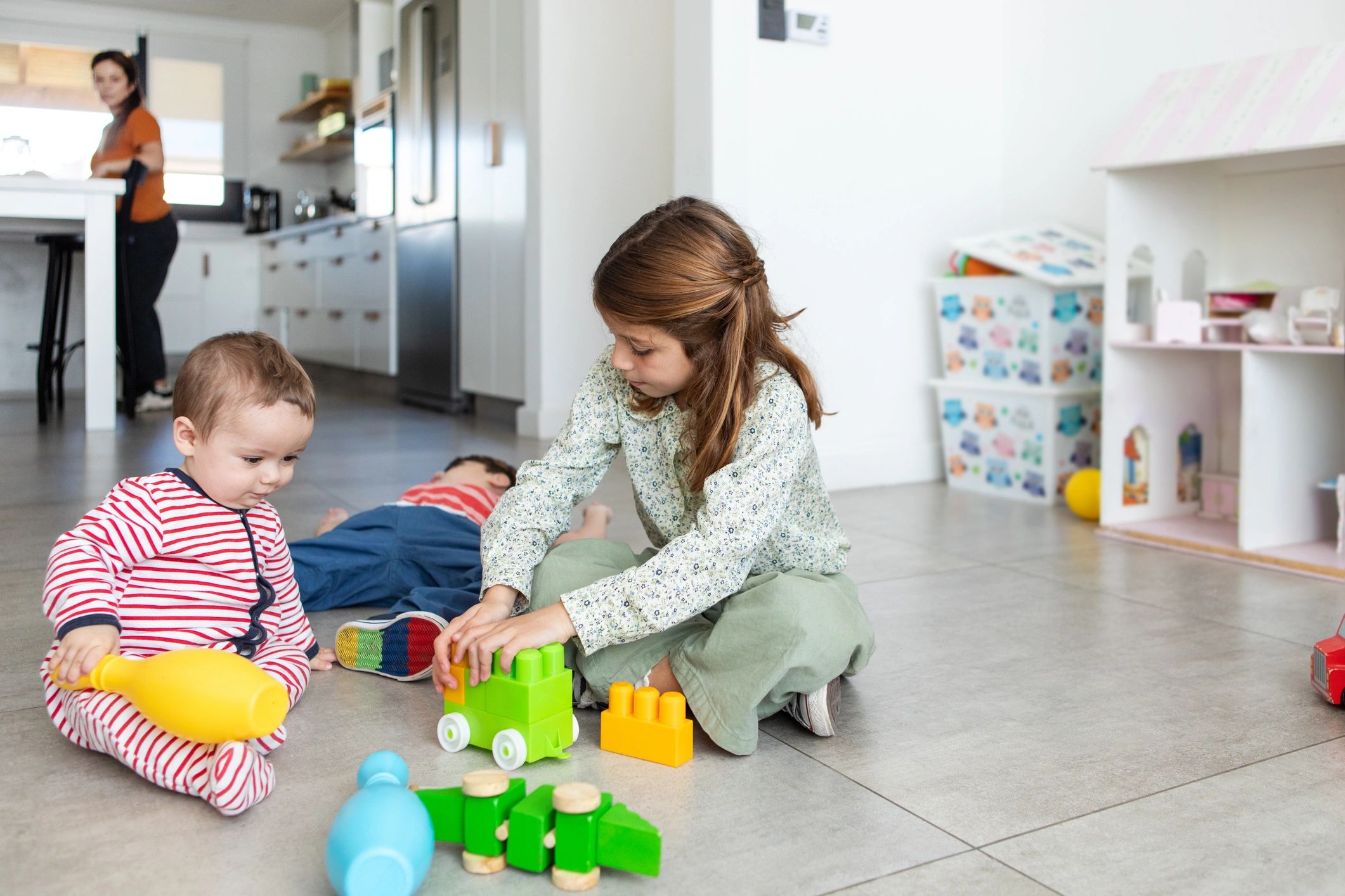 Three siblings playing with toys on the floor