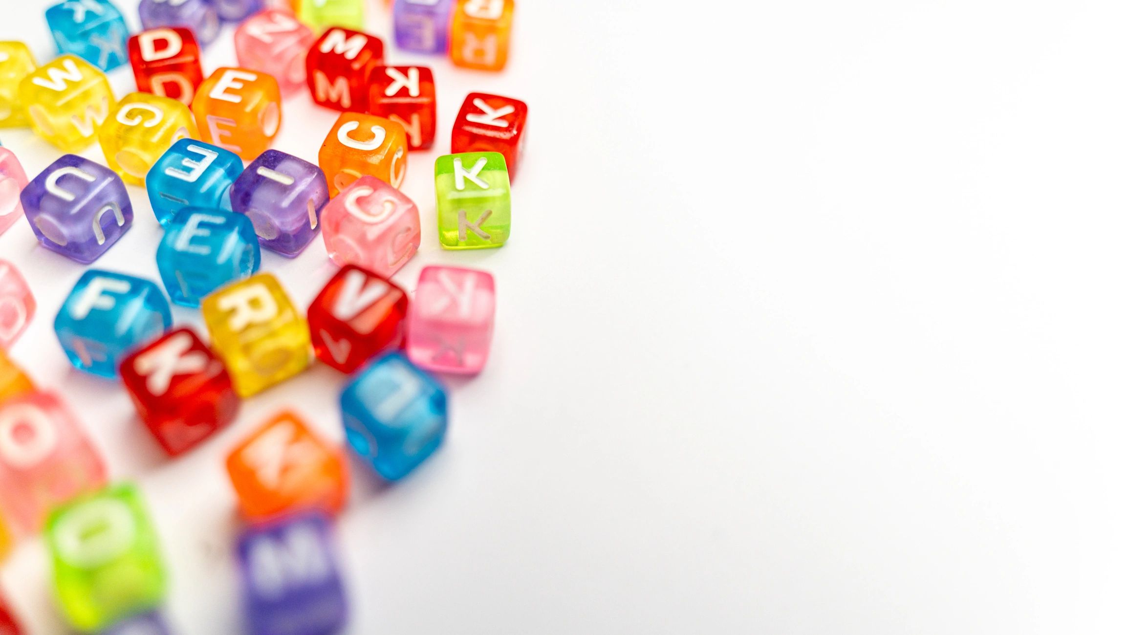 Colourful alphabet beads scattered on a white surface